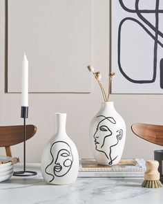 two vases sitting on top of a table next to a candle and some books