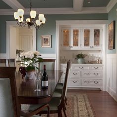 a dining room table with chairs and a wine bottle on top of it in front of a white cabinet