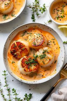 two bowls filled with soup and topped with scallops