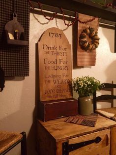 a wooden table topped with a potted plant next to a wall mounted plaque that reads, i drink for the thirsty food for the hungry