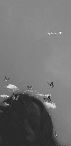 a black and white photo of a woman's head with butterflies in the sky