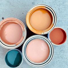 four different colors of paint sitting on top of each other next to each other in cans