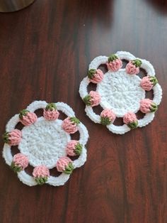 two crocheted coasters sitting on top of a wooden table