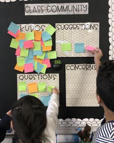 two children writing on a bulletin board with sticky notes