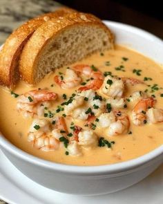 there is a bowl of soup with shrimp and bread