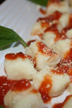 some food is sitting on a plate with sauce and green leafy leaves in the background