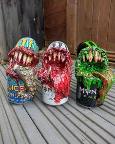 three decorated cans sitting on top of a wooden table next to each other with teeth