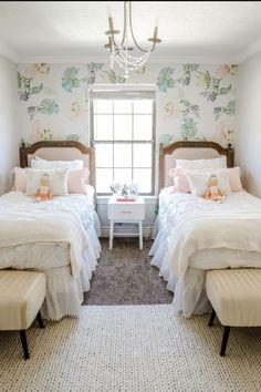 two twin beds in a bedroom with floral wallpaper and chandelier above them