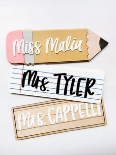 three wooden name tags with pencils on them