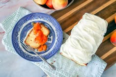 a piece of cake on a blue and white plate next to some peaches in a bowl