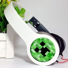 a white headphone with a green face on it next to a potted plant