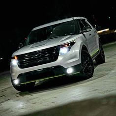 a white suv driving down a street at night with its lights on and headlamps on