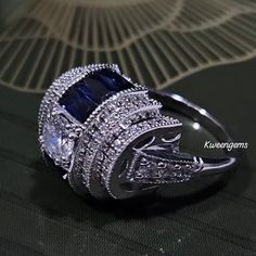 a fancy ring with blue and white stones on it's sides, sitting on top of a table