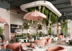 the interior of a restaurant with pink and green chairs, tables and umbrellas hanging from the ceiling