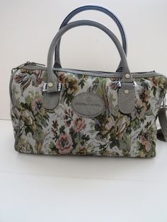 "When traveling you'll want a capacious bag for all the items a seasoned traveler wants at hand. This vintage American Flyer tote is just what you need for holding carry on items, your IPad and other miscellaneous items. The tapestry fabric is gray with pink flowers and green accents. The tote opens at the top with a heavy duty zipper, has two handles PLUS an over the shoulder strap (great for hands free carrying. There are 4 silver bumper feet to protect the tote from getting wet or banged up. Carry On Tote, Tapestry Handbags, Makeup Travel Case, Makeup Travel, Mod Cloth Dresses, Vintage Luggage, Carry On Luggage, Grey Floral, Satchel Handbags