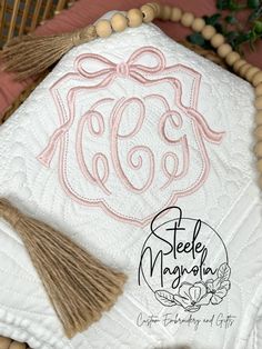 an embroidered monogrammed pillow with tassels on it