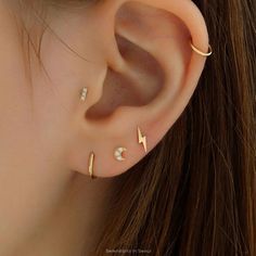 a woman wearing gold ear piercings with lightning bolt and stars on the back of her ear