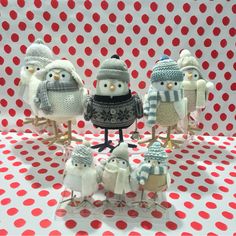 small knitted birds with hats and scarves on their heads are standing in front of a polka dot background