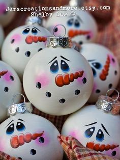 some white ornaments with faces painted on them are sitting in a pile and have eyes drawn on them