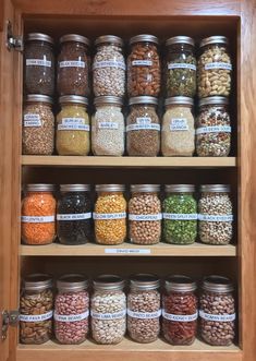 an open cabinet filled with lots of different types of beans and cereals in jars