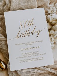 a white and gold 50th birthday party card on a table with flowers in the background