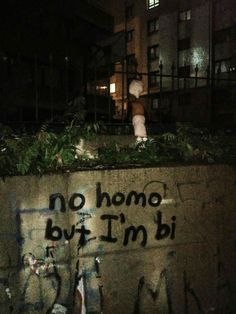 graffiti written on the side of a concrete wall in front of a building at night