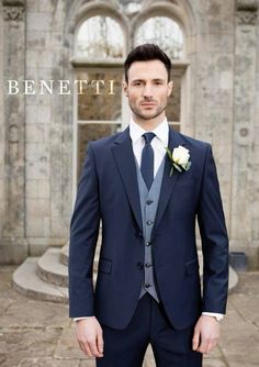 a man wearing a suit and tie standing in front of a building