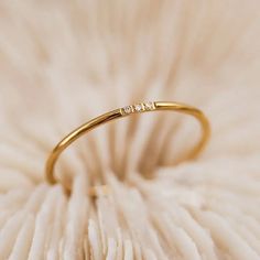 a gold ring with three small diamonds on it's side sitting on a white flower