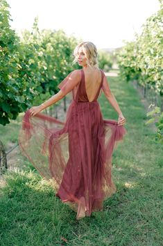 a woman in a red dress is walking through the grass