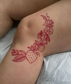 a woman laying on top of a bed with a strawberry tattoo on her arm and leg