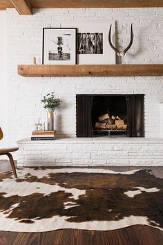 a living room with a fireplace and pictures on the wall, including an animal skin rug