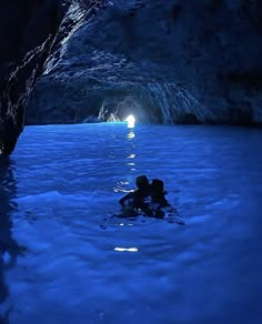 a person swimming in a blue cave with light coming from the water's entrance