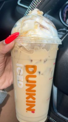 a person holding up a drink in their hand with the word dunkin'donuts on it