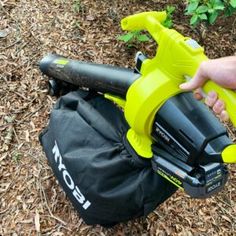 a person holding an electric blow dryer in their hand next to a bag on the ground