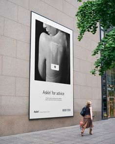 a woman walking past a large advertisement on the side of a building with an ad