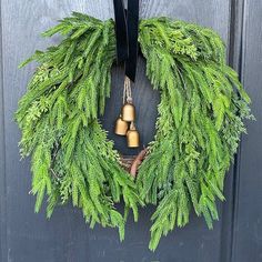 a wreath with two bells hanging from it's side on the front door,