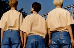 three women in blue leather pants standing next to each other with their backs turned towards the camera