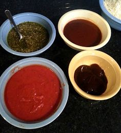 four bowls filled with different types of sauces on top of a black countertop