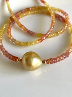 "Petite sapphires, 2-4mm, ranging in color from yellow to peach, orange, and red, frame a gorgeous 10mm gold South Sea pearl.   The golden color is intense! Necklace measures 16\" with 14K gold-filled findings, and comes with a 2\" gold-filled extender chain to bring it to 18\".  Works great as a versatile layering piece, or shines all on its own.   Your jewelry will come gift-boxed, and gift-wrapping is available upon request.  Thanks for checking out my shop!" Yellow Gold Beaded Necklaces With Natural Stones, Gold Rondelle Natural Stones Gemstones, Gold Single Strand Gemstones As Gift, High Luster Yellow Gold Pearl Necklace With Round Beads, Yellow Gemstone Beaded Necklaces With Round Beads, Yellow Gemstone Jewelry With Round Beads, Yellow Gold Pearl Necklace With Gemstone, Yellow Gemstone Round Beads Jewelry, Gold Briolette Pearl Necklace With Gemstone