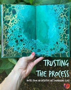 a hand holding up an open book with blue and green ink on it, which reads trusting the process notes from an interactive art journal class