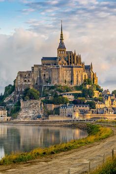 an old castle sits on top of a hill next to the water in front of it