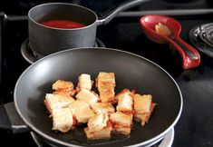 tofu cubes are being cooked in a pan on the stove top with sauce