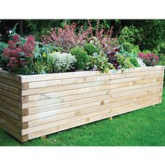 a large wooden planter filled with lots of different types of flowers and plants in it