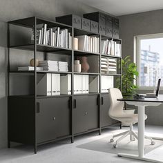 a room with a desk, bookcases and chairs in front of a window