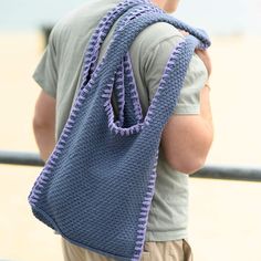 a man carrying a blue crocheted bag on his back with the handle down