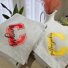 two personalized t - shirts with the letter c on them are sitting next to a vase