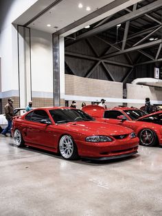 two red cars are parked in a garage