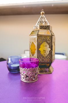 a purple candle sits on a table next to a lantern