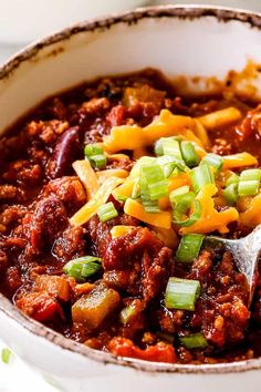 a white bowl filled with chili and cheese