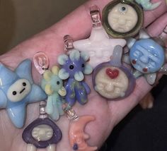 a person's hand holding several different shaped charms